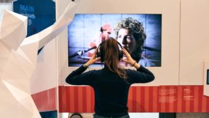 Une femme regarde un écran vidéo à la Maison olympique canadienne