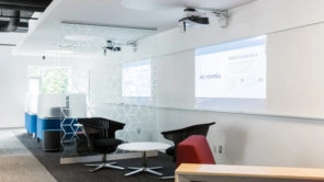 Salle commune de coworking avec projecteurs au mur et fauteuils